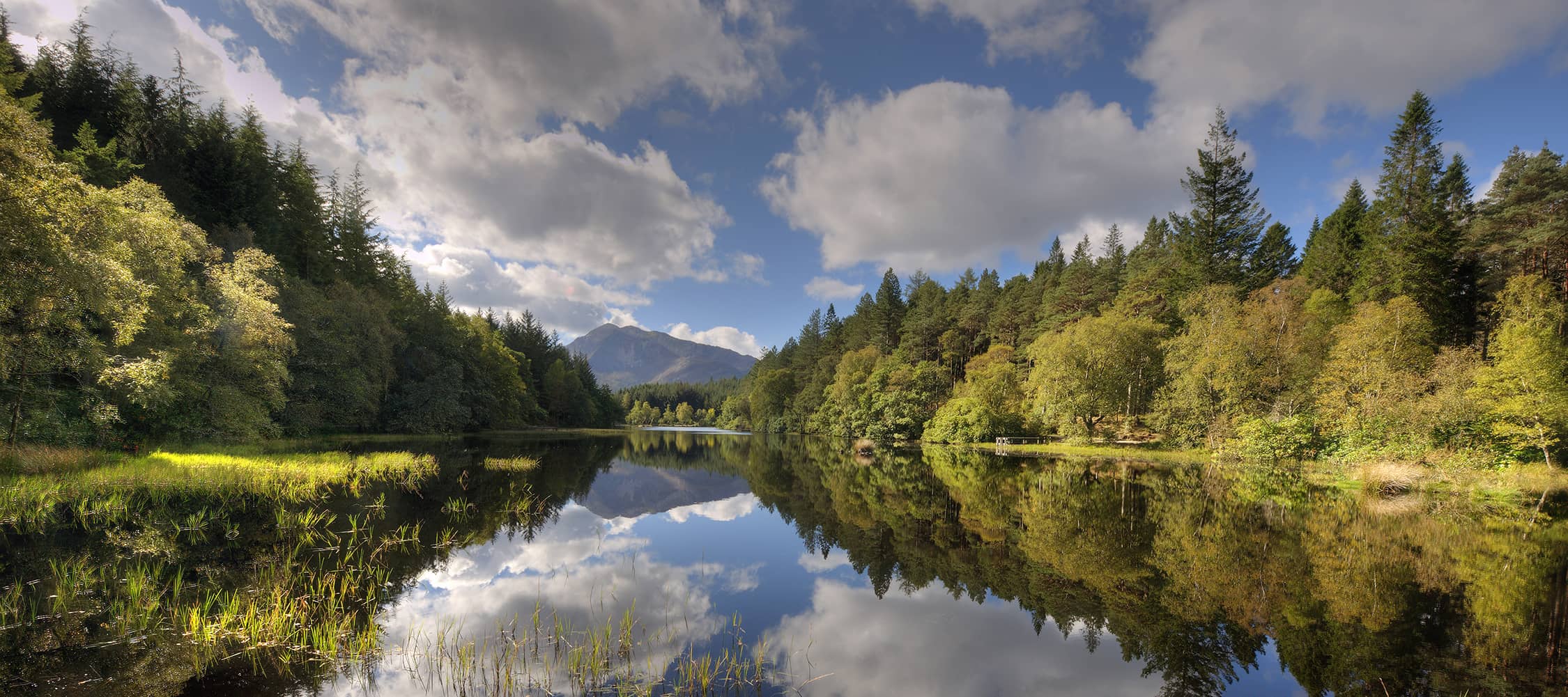 Scenic view of Glencoe mountain trail with lush greenery and towering peaks in the Scottish Highlands